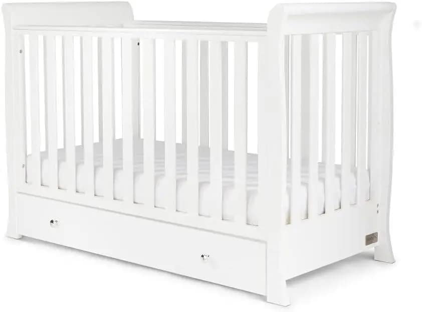 A white wooden crib with vertical slats and a drawer underneath, featuring a simple and modern design.